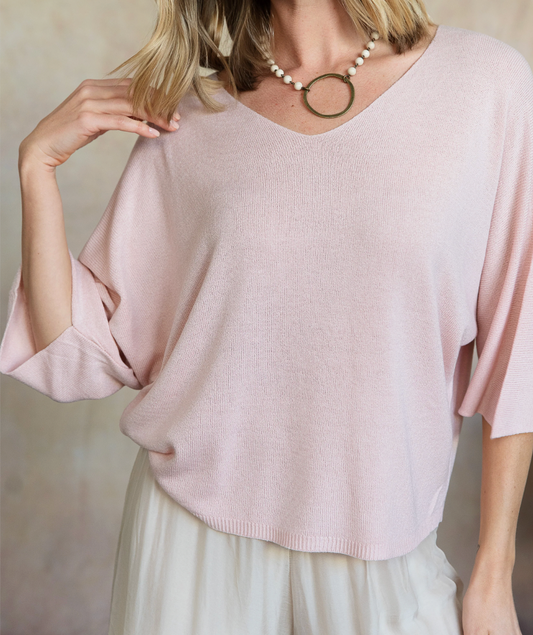 Light pink sweater worn by a person against a neutral background