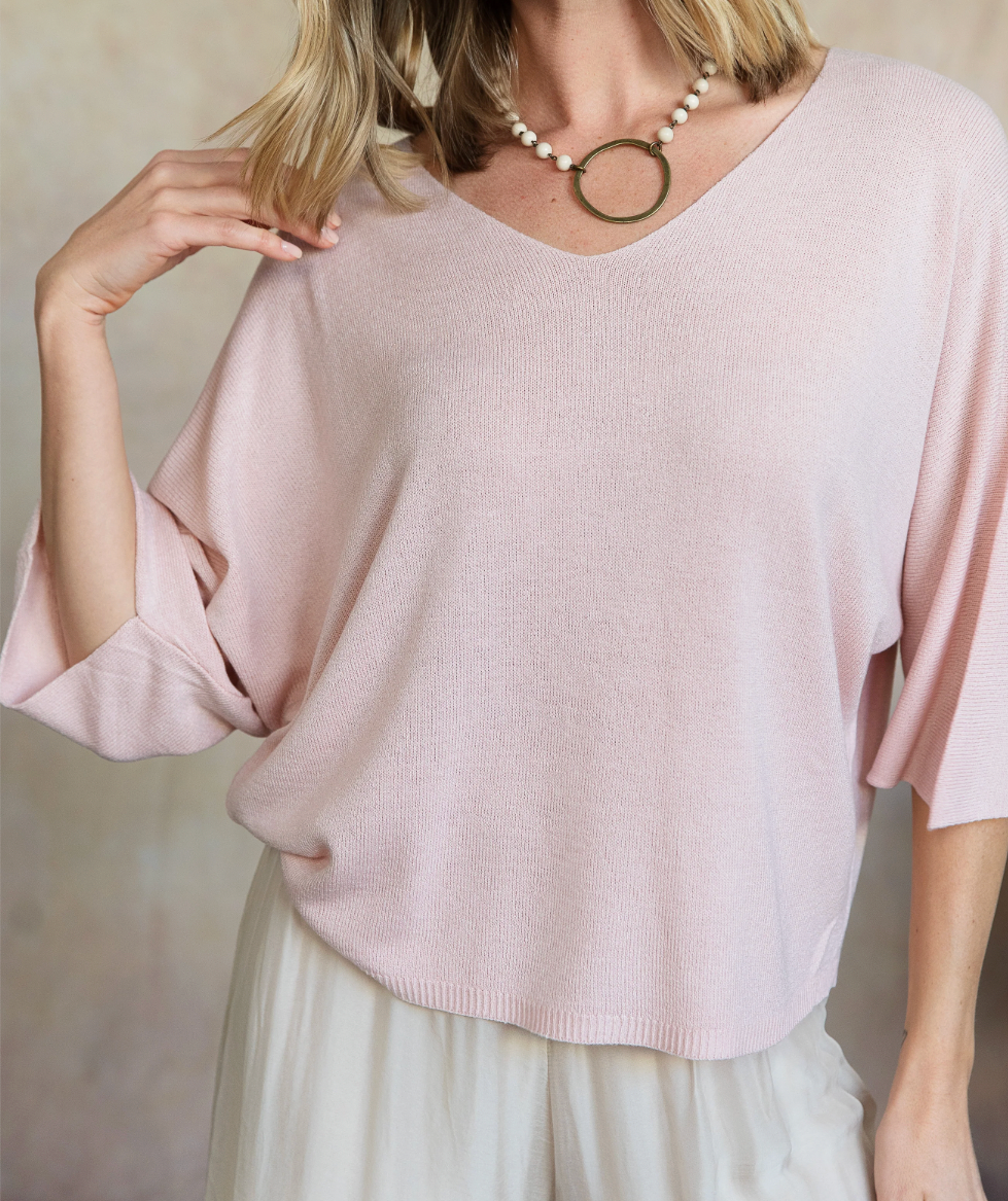 Light pink sweater worn by a person against a neutral background