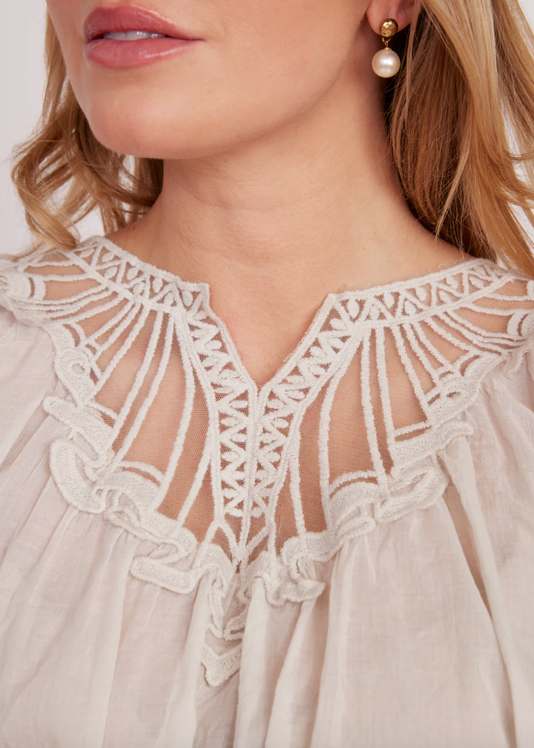 Close-up of a woman wearing a white lace dress with a pearl earring.