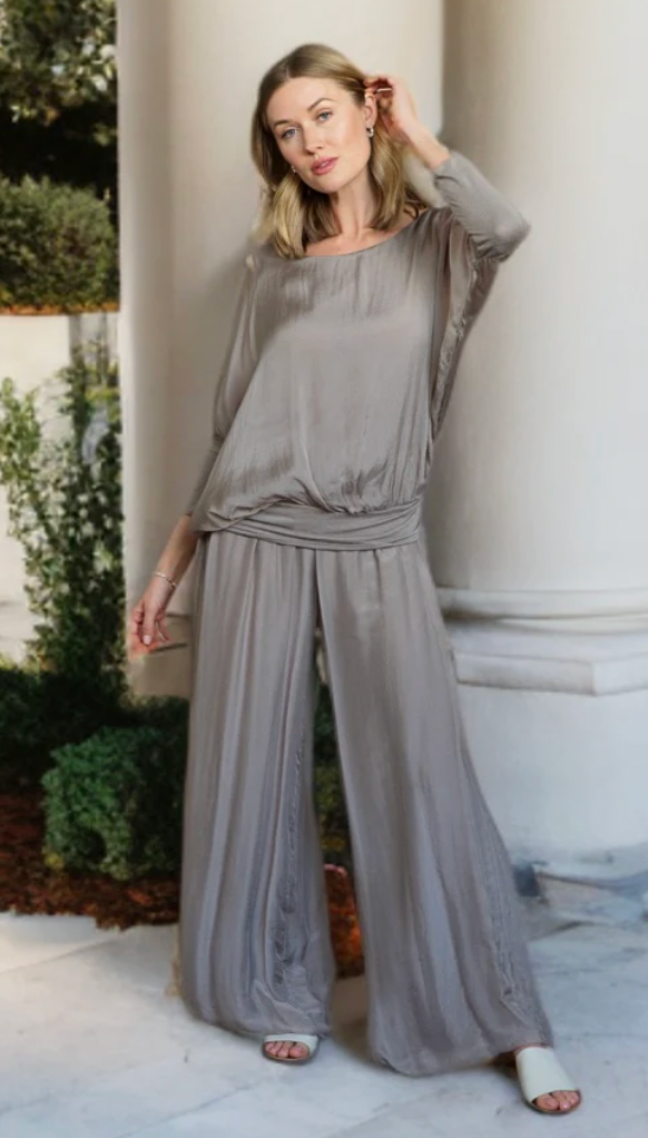 Woman wearing a gray outfit standing outdoors with classical architecture in the background