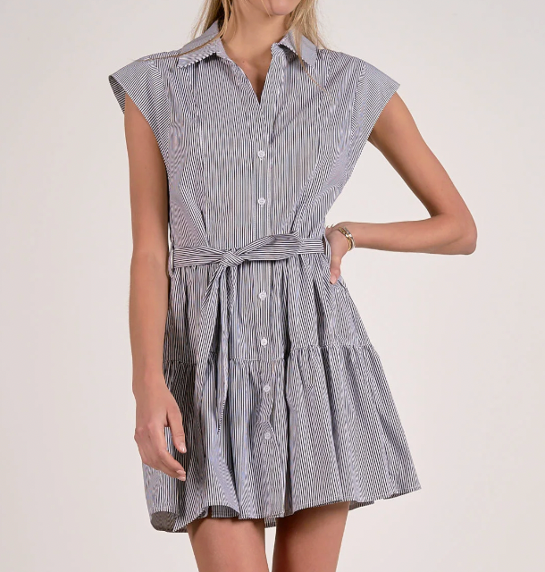 Woman wearing a sleeveless striped dress with a belt on a plain background