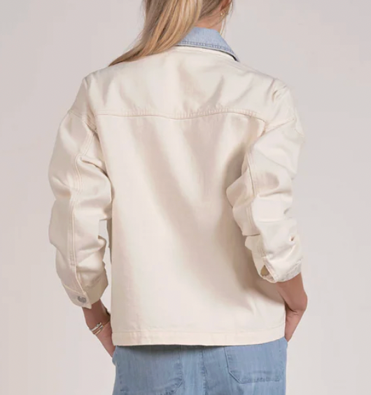 Person wearing a beige jacket and blue jeans on a plain background