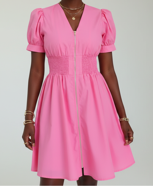 Woman wearing a pink dress with puff sleeves against a white background