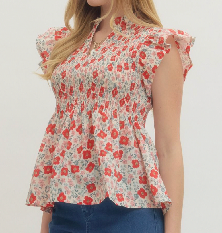 Woman wearing a floral blouse with red flowers on a plain background