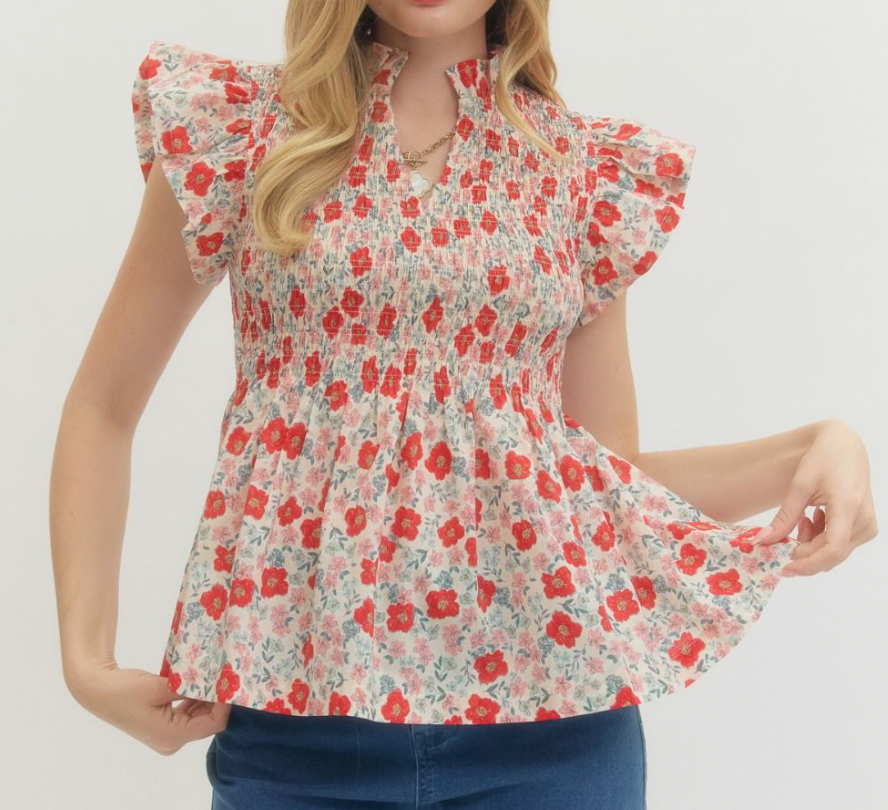 Woman wearing a floral blouse with red and white flowers on a plain background