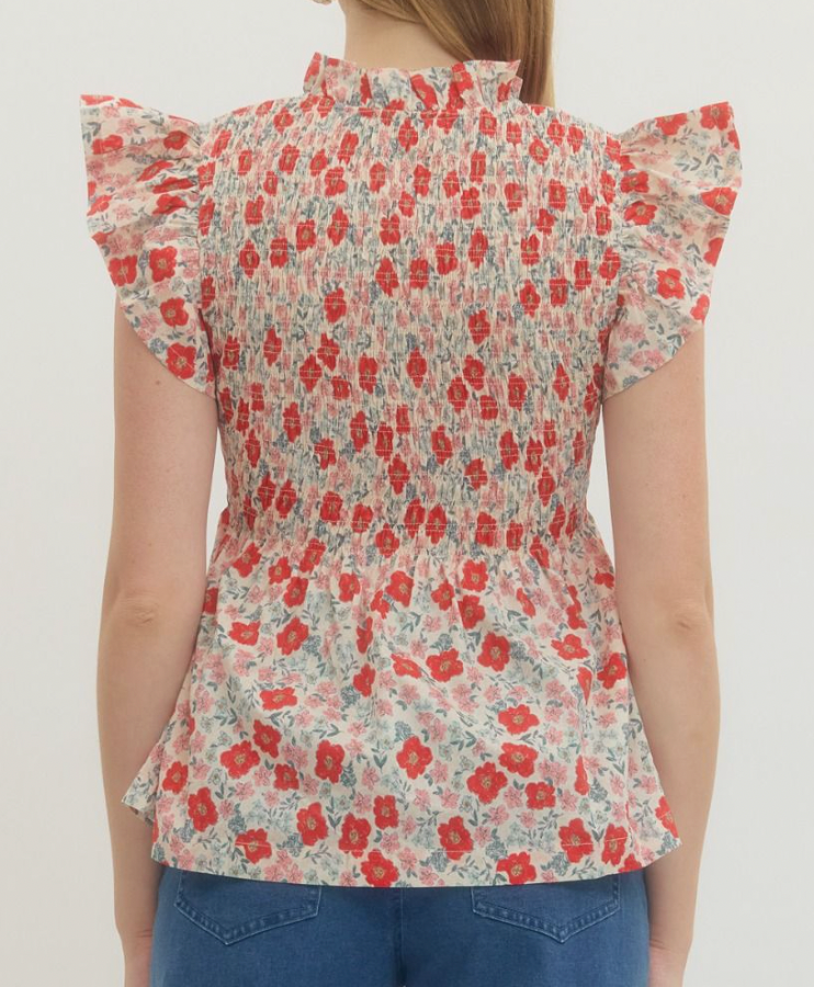 Floral blouse with ruffled sleeves worn by a person on a plain background