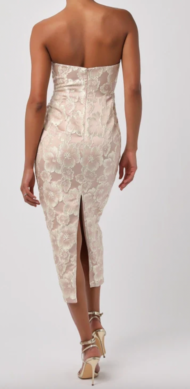 Woman wearing a strapless, floral-patterned dress with a slit on a white background