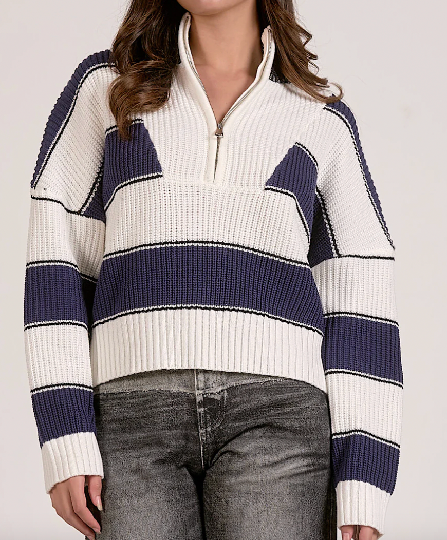Person wearing a white and blue striped sweater with a plain background