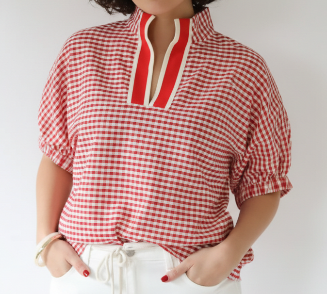 Red and white checkered blouse with a high neckline worn by a person against a plain background