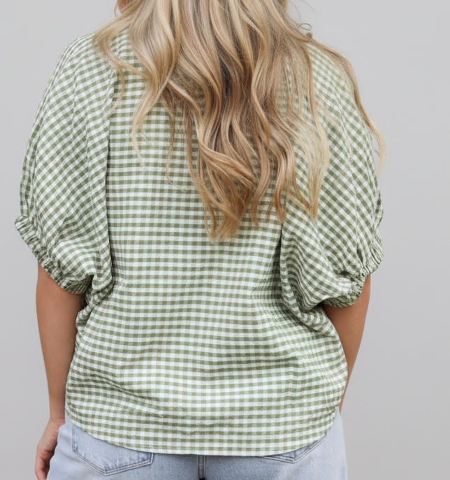 Person wearing a green and white checkered shirt on a wooden deck.