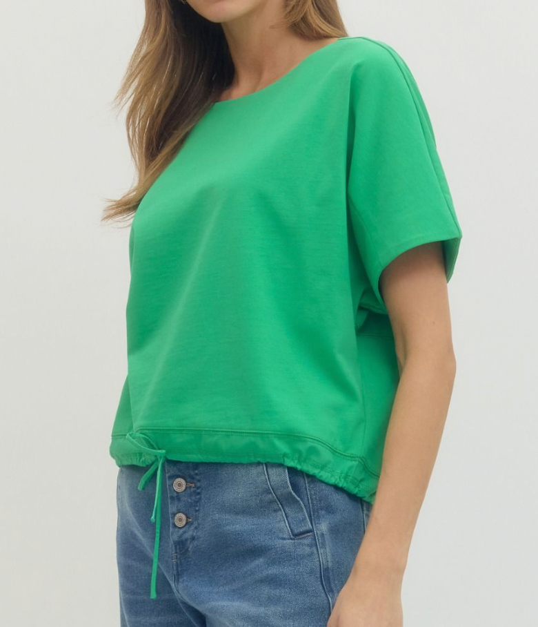 Person wearing a green top and blue jeans on a plain background