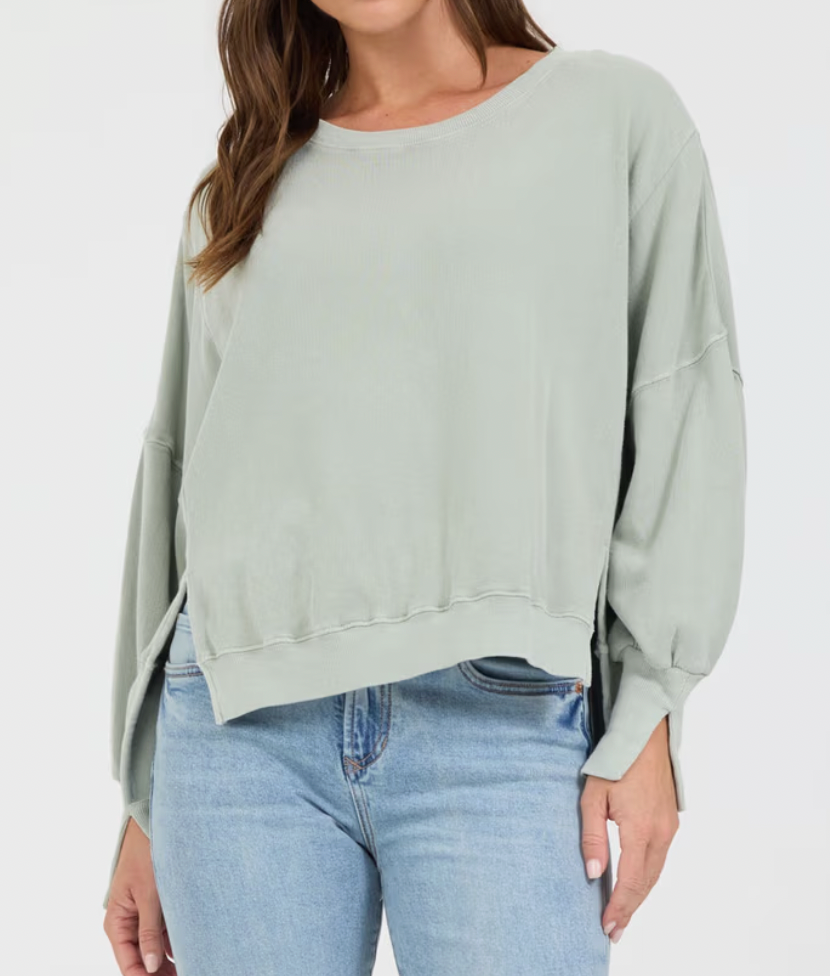 Woman wearing a light green sweater and blue jeans on a white background