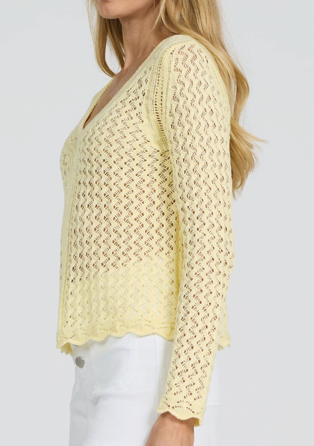 Woman wearing a light yellow crochet top against a white background