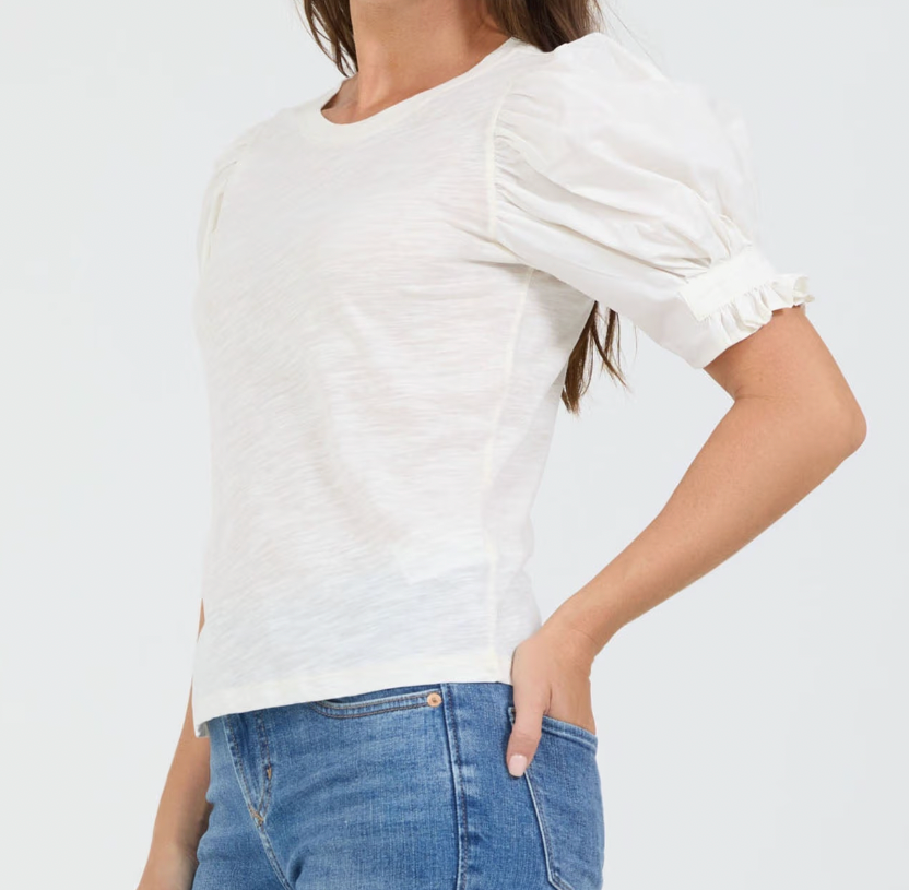 Person wearing a white blouse and blue jeans on a plain background