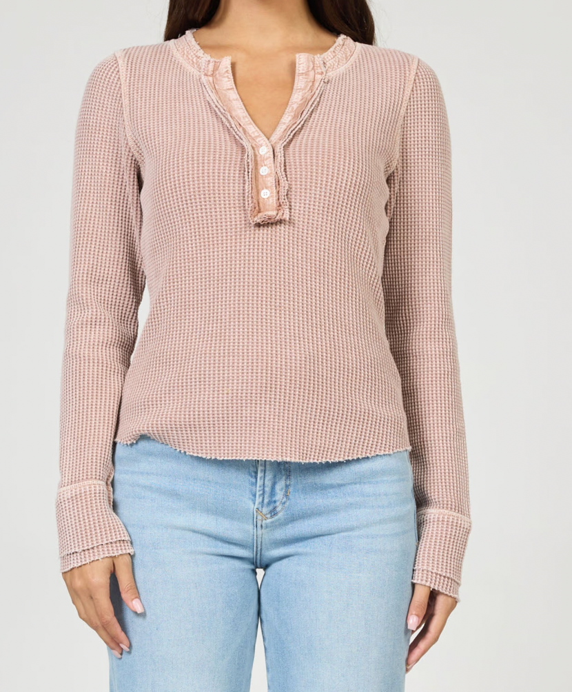 Person wearing a pink checkered long-sleeve top and light blue jeans on a white background