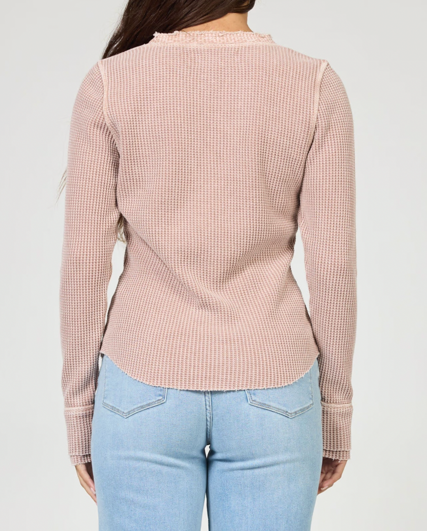 Person wearing a pink checkered long-sleeve top and light blue jeans on a white background