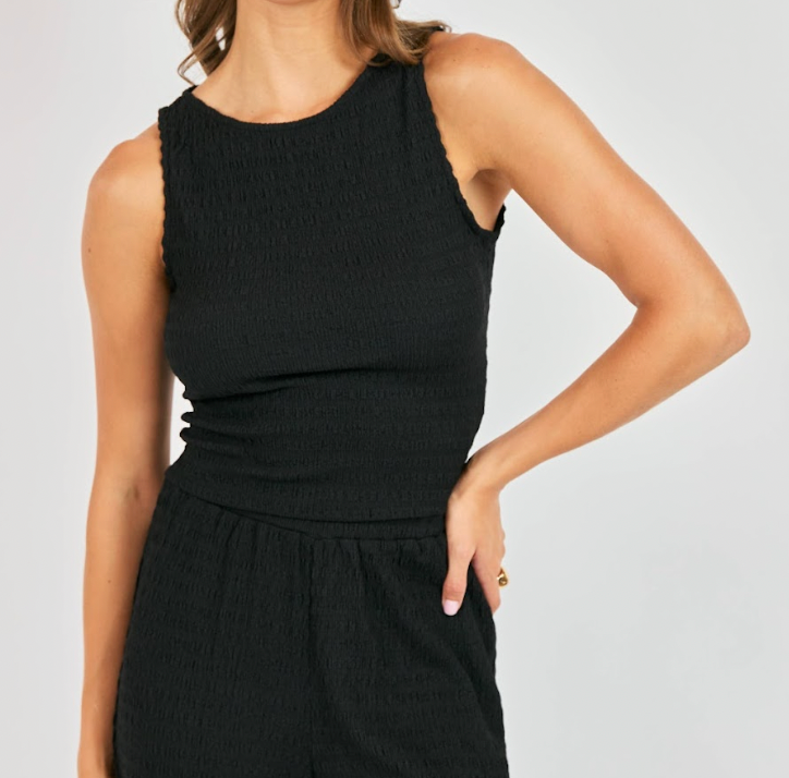 Person wearing a black sleeveless top and black pants on a plain background