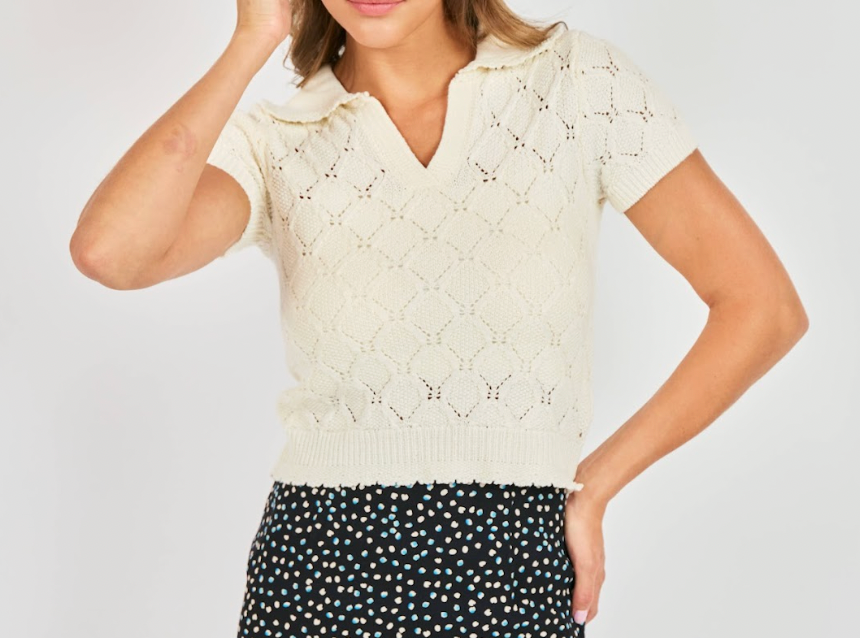 Woman wearing a cream knitted top with a plain background