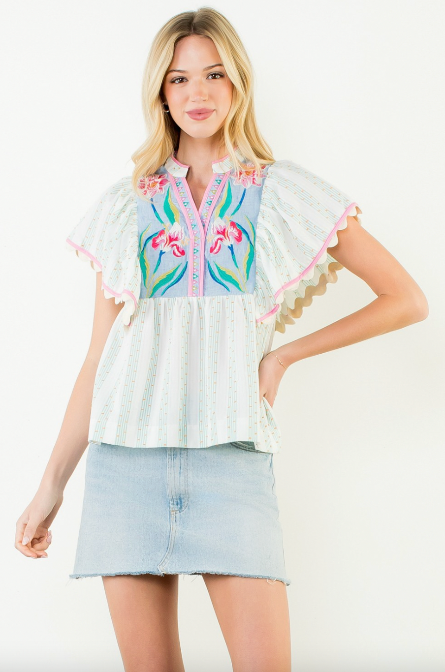 Woman wearing a colorful embroidered blouse with ruffled sleeves on a white background
