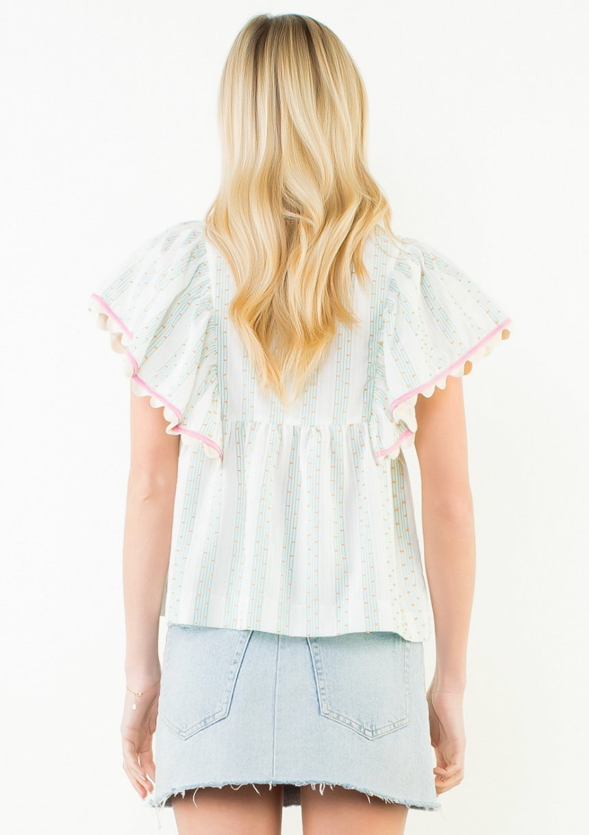 Woman wearing a white blouse with ruffled sleeves and a denim skirt on a white background