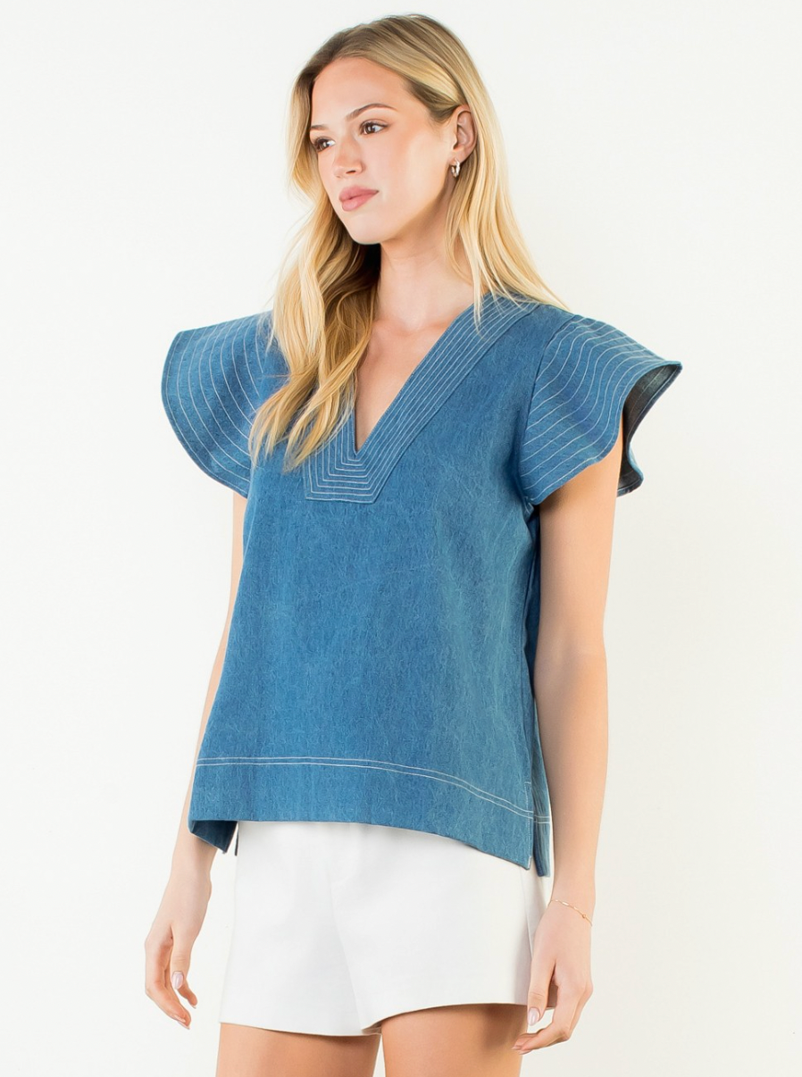 Woman wearing a blue top with white trim on a white background