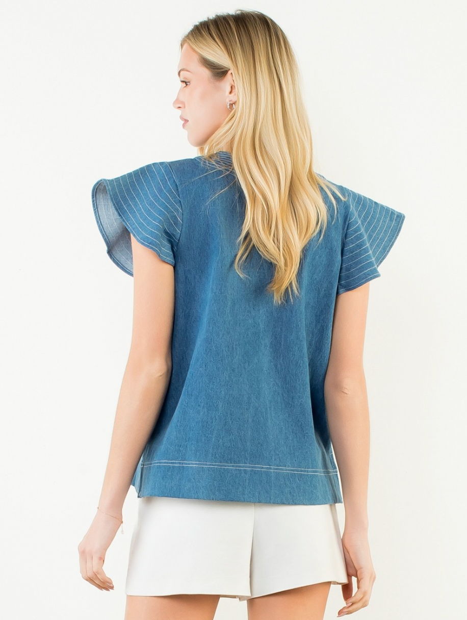 Woman wearing a blue denim top and white skirt on a light background