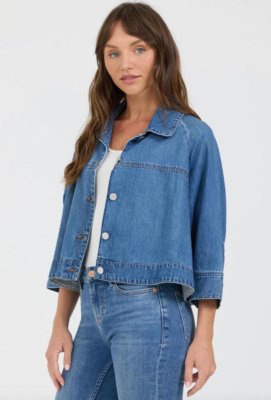 Woman wearing a blue denim jacket and jeans on a white background