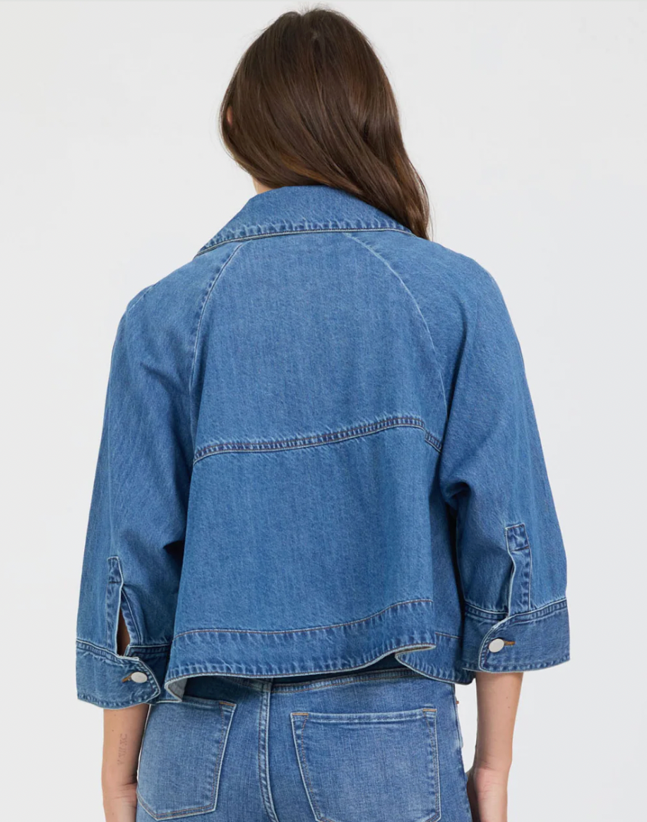 Person wearing a blue denim jacket on a white background