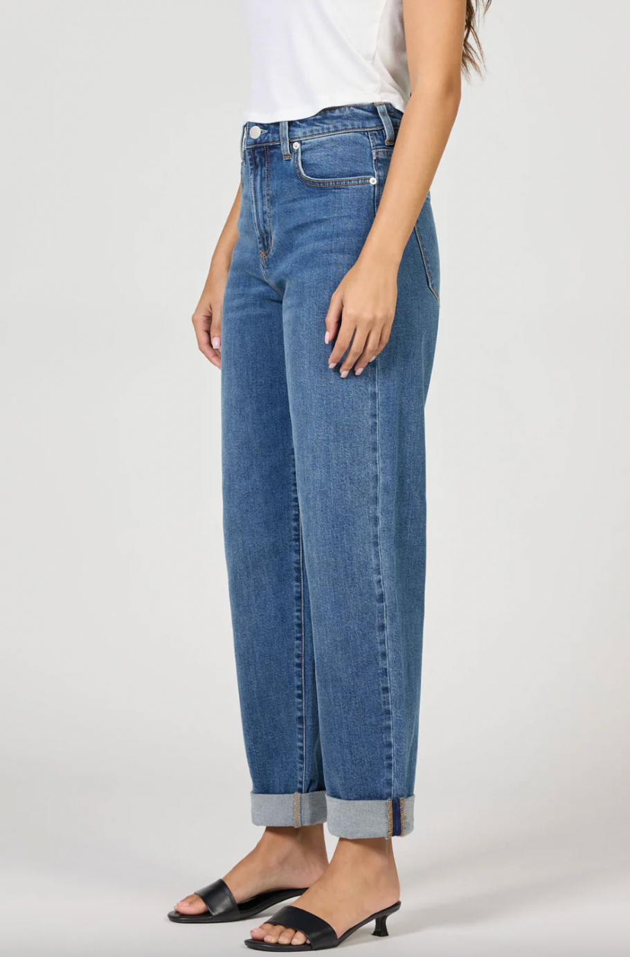 Person wearing blue jeans on a plain background