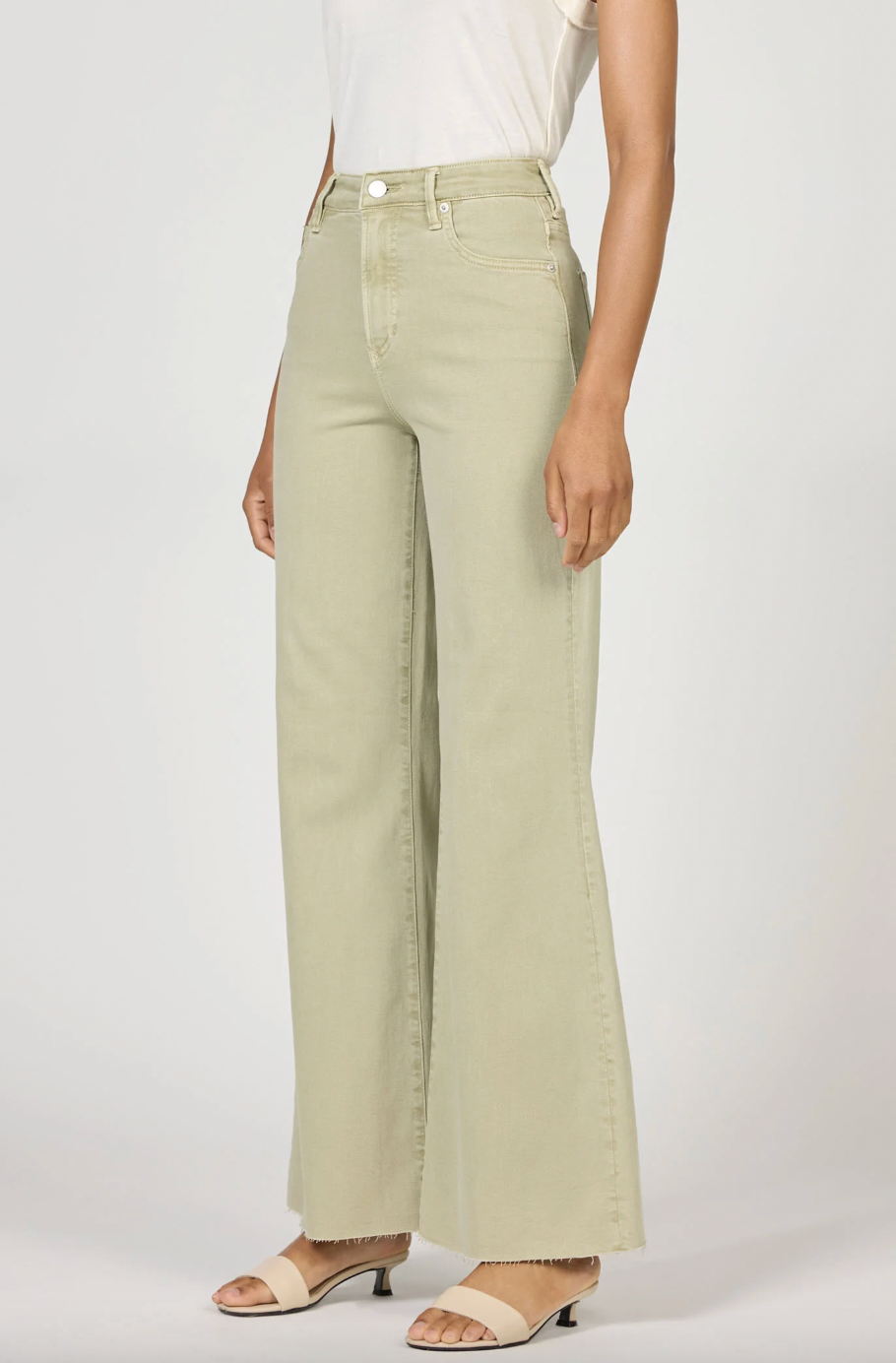 Person wearing light green wide-leg jeans on a white background