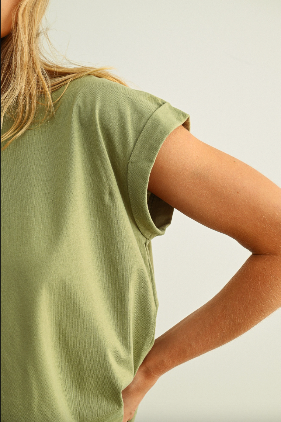 Person wearing a green sleeveless top against a neutral background