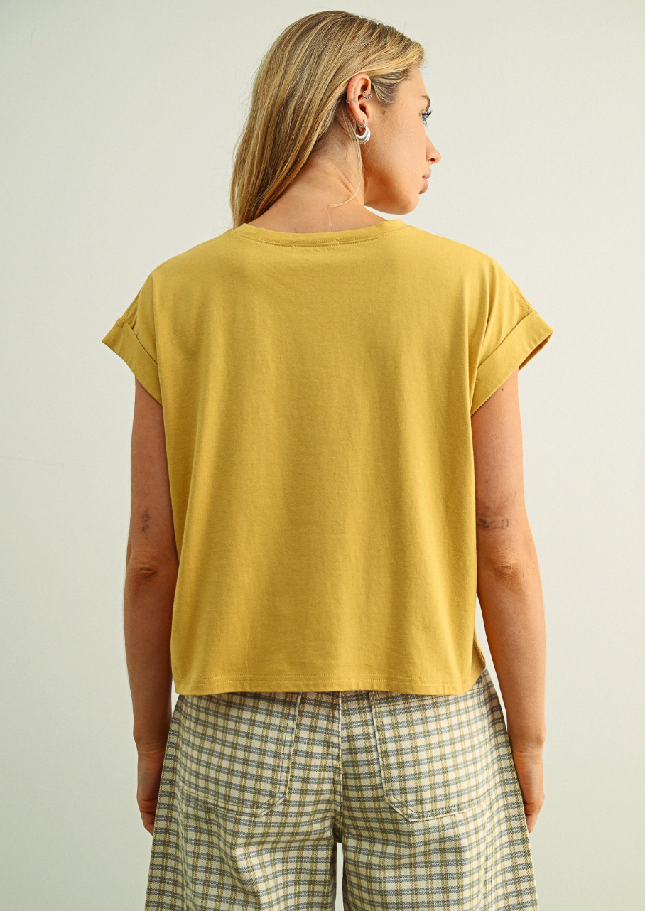 Person wearing a mustard yellow t-shirt and plaid pants on a plain background