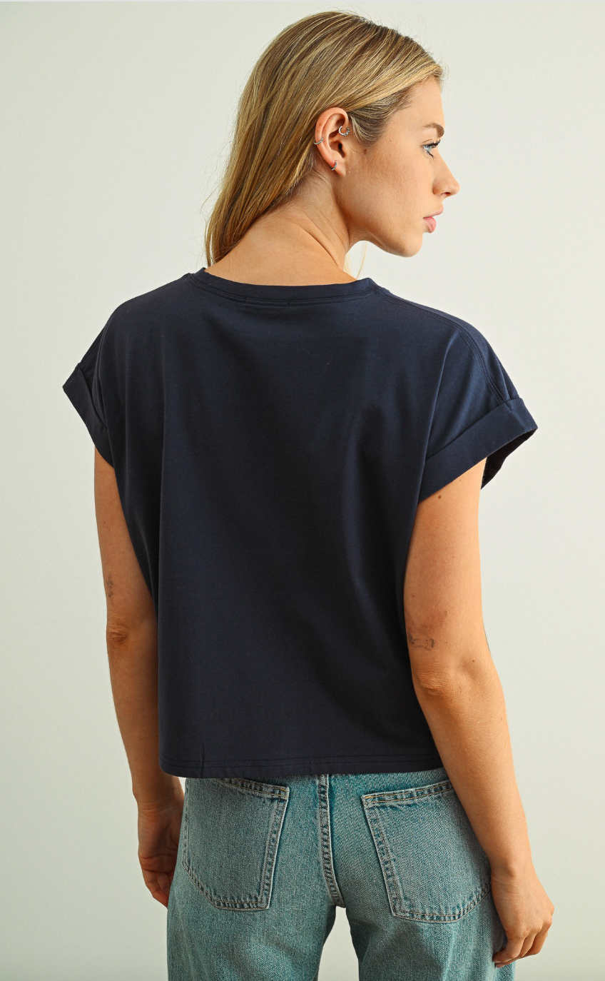 Person wearing a navy blue t-shirt and light blue jeans on a plain background