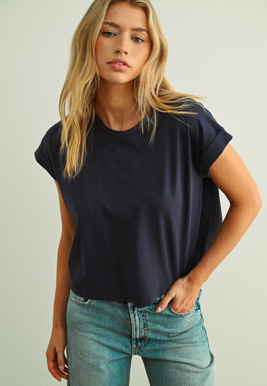 Woman wearing a black t-shirt and blue jeans against a plain background