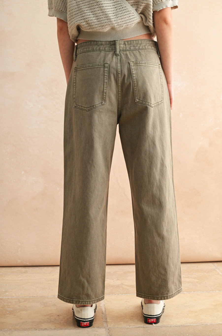 Person wearing olive green wide-leg pants against a beige background