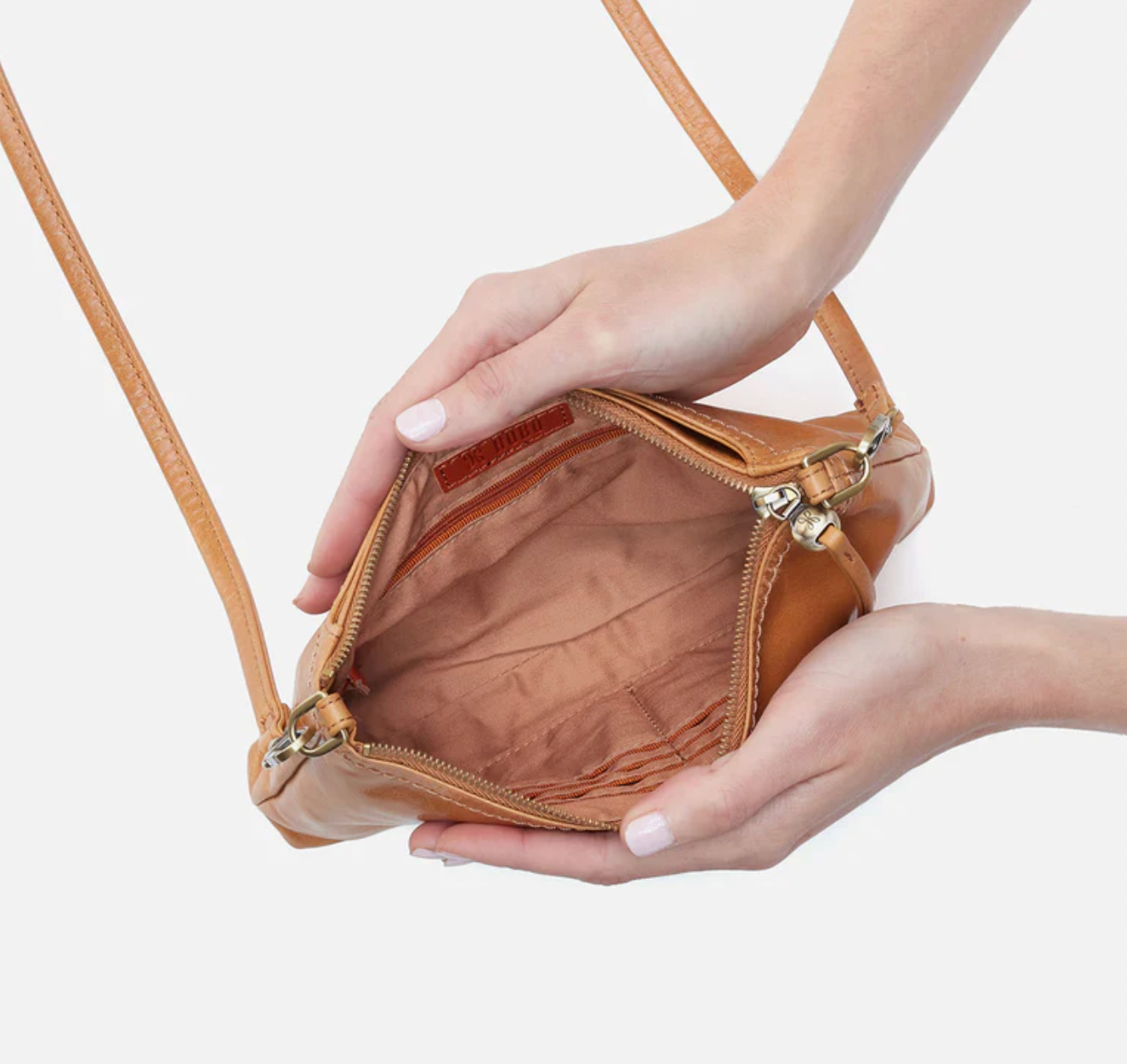 Brown leather handbag held by a person against a light background