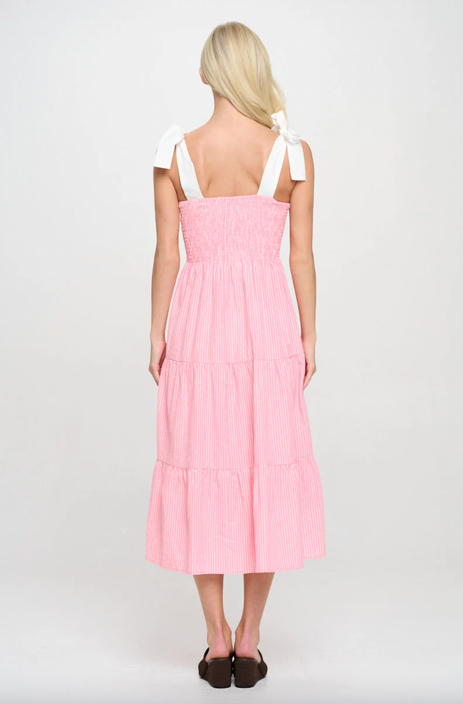 Person wearing a pink dress with white straps on a white background
