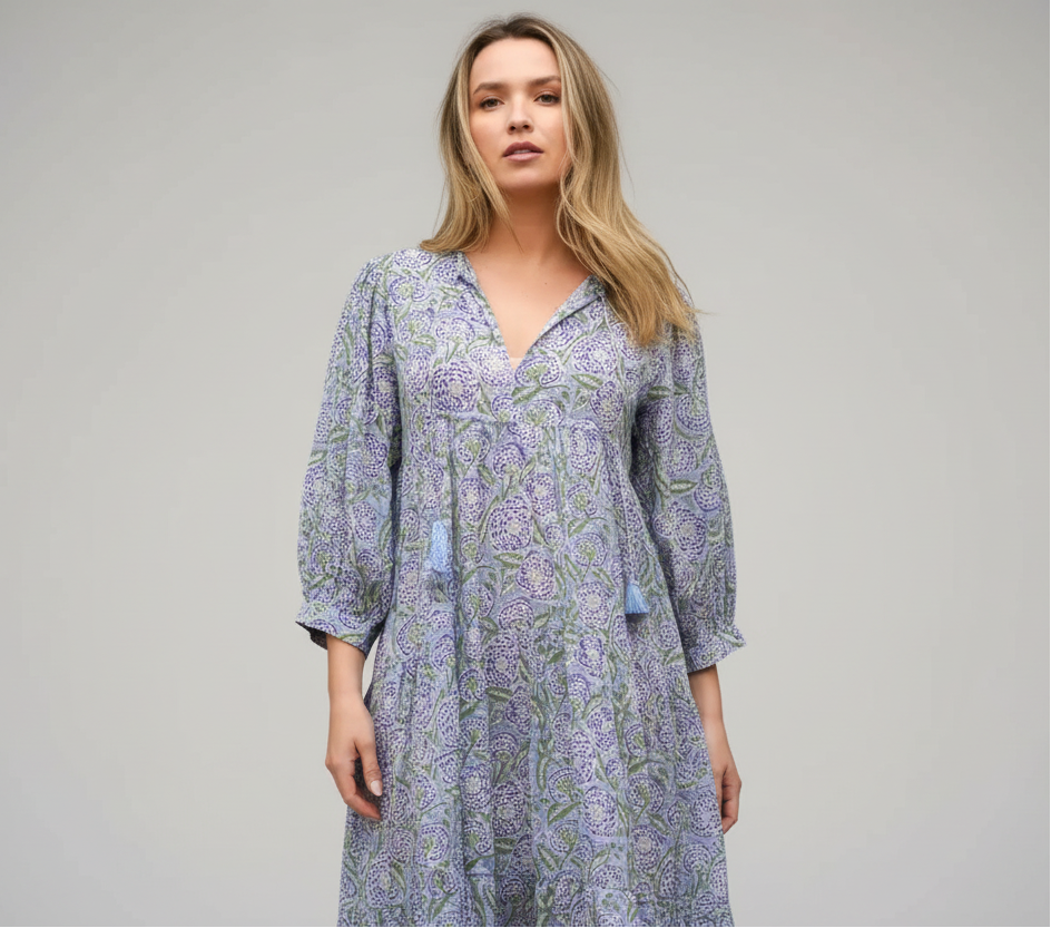 Woman wearing a long, patterned dress against a plain background