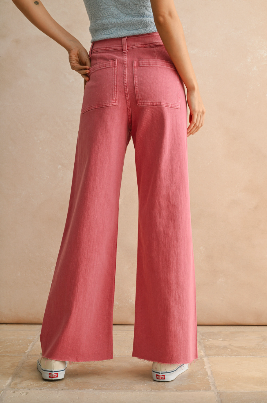 Person wearing pink wide-leg jeans against a beige background