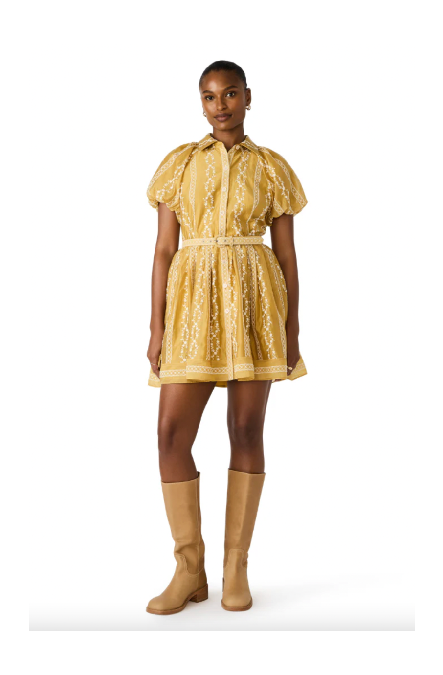 Woman wearing a yellow dress with puffed sleeves and beige boots on a white background