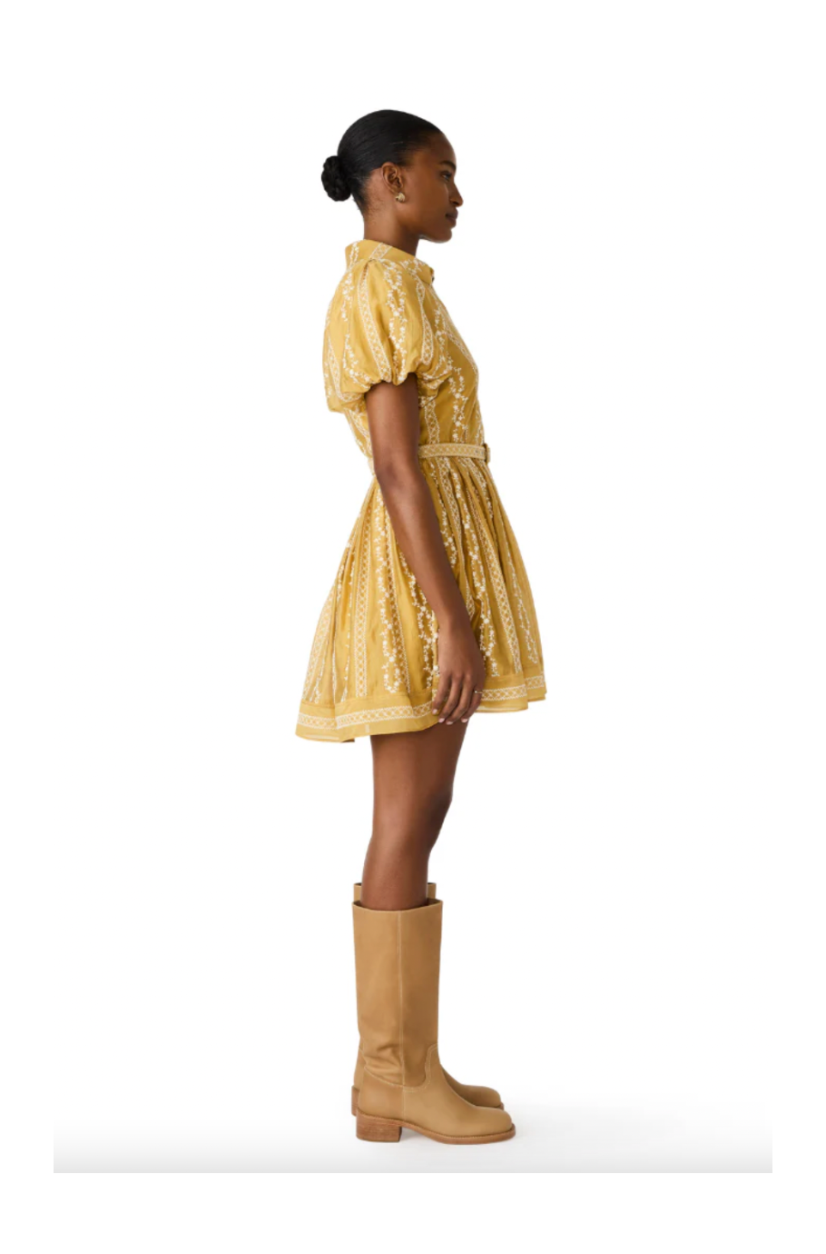 Woman wearing a yellow dress and tan boots on a white background