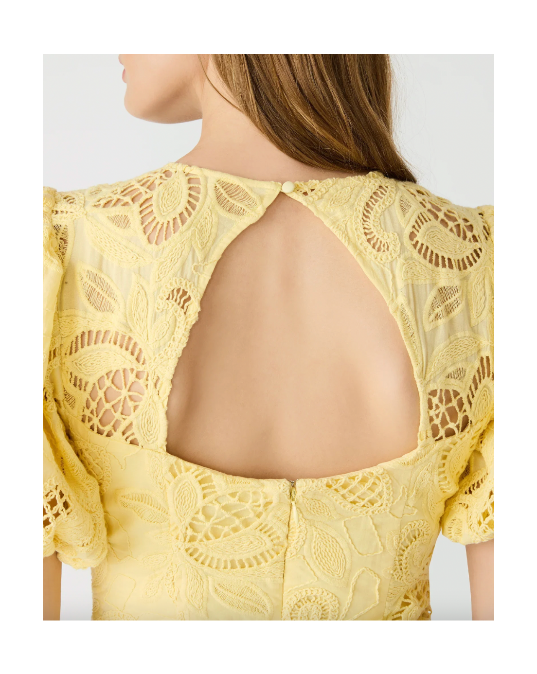 Yellow lace dress with open back on a plain background