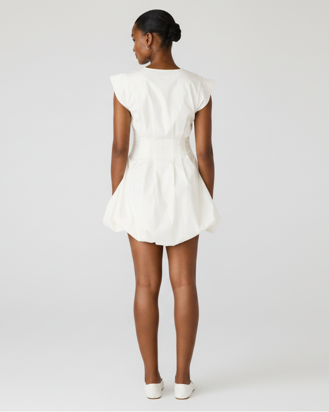 Person wearing a white dress with cap sleeves on a white background