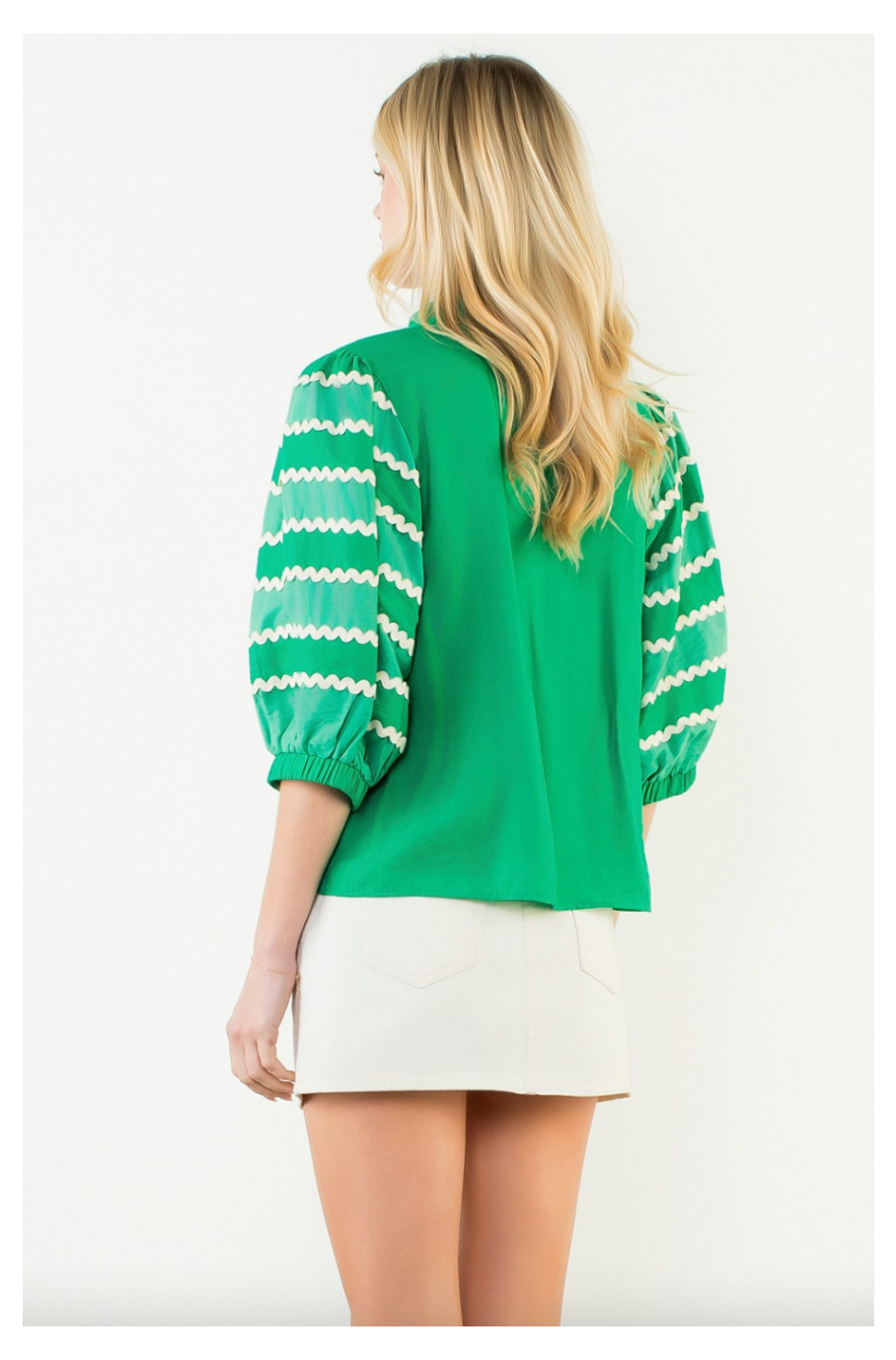 Woman wearing a green and white striped blouse with a plain background