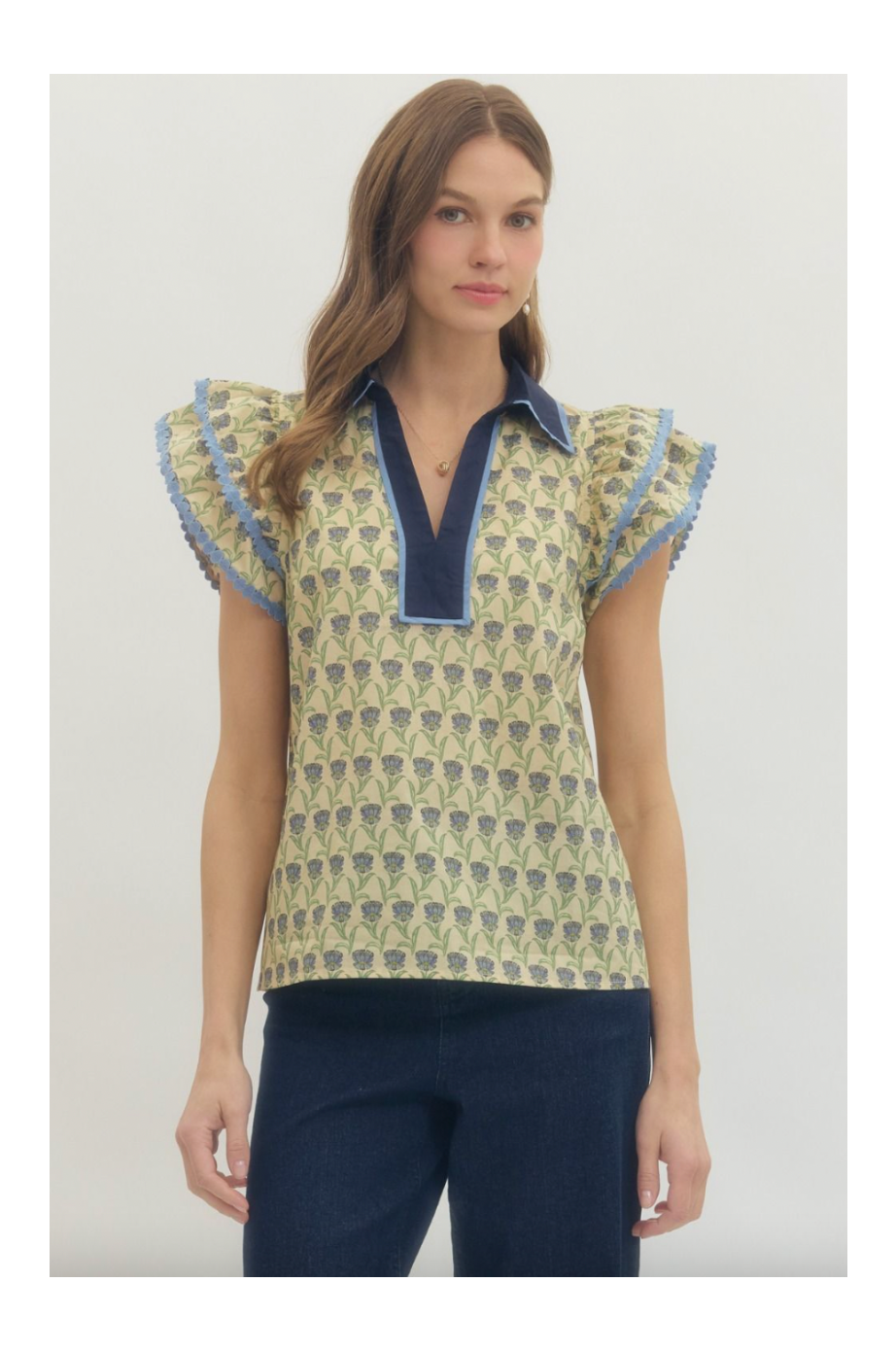 Woman wearing a patterned top with ruffled sleeves on a plain background