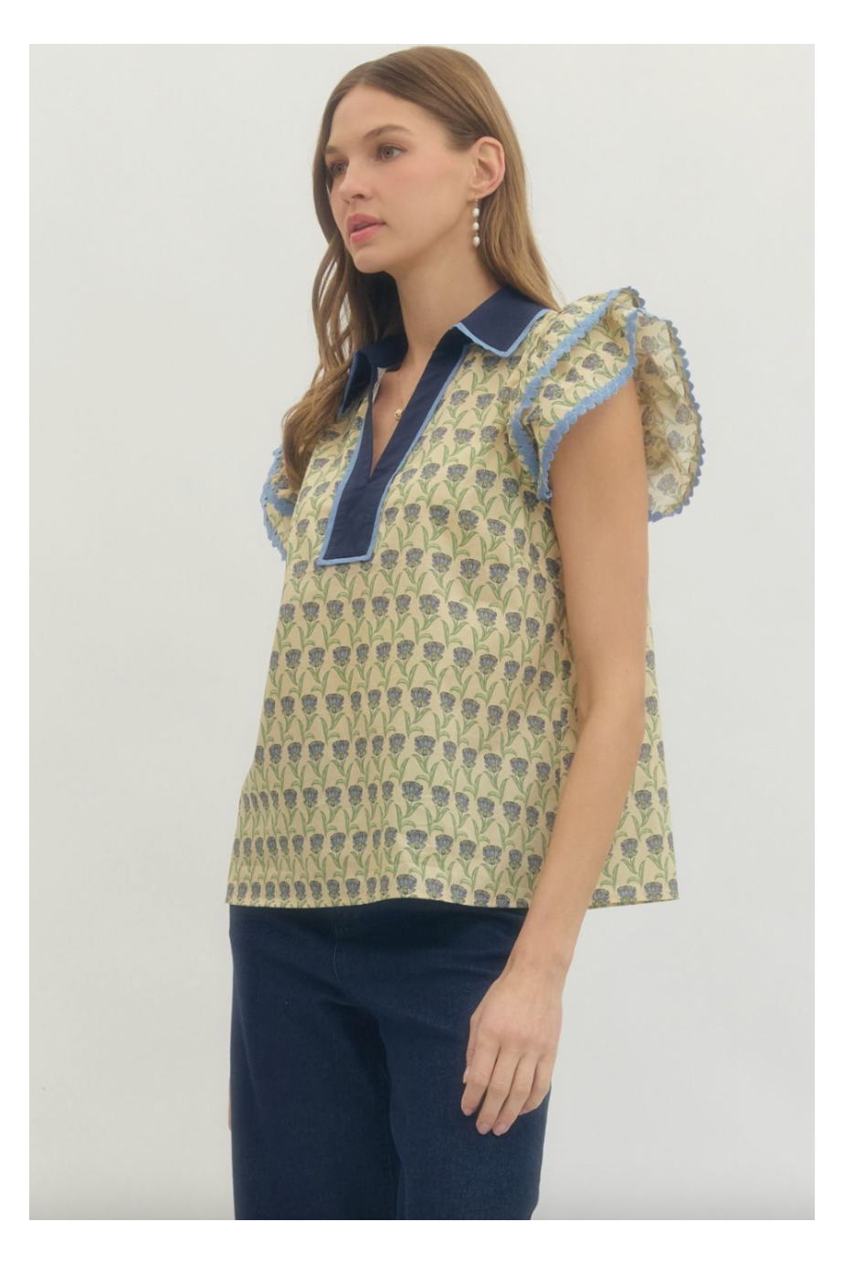 Woman wearing a patterned top with ruffled sleeves on a white background
