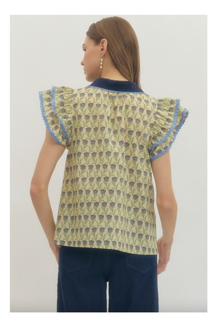 Woman wearing a patterned top with ruffled sleeves on a white background
