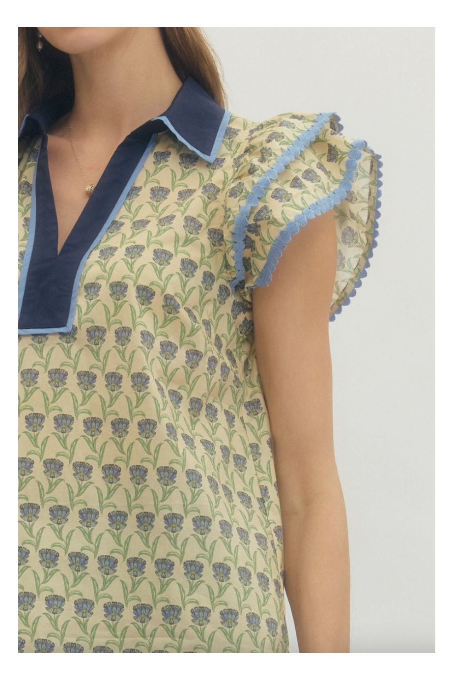 Woman wearing a patterned top with ruffled sleeves on a white background