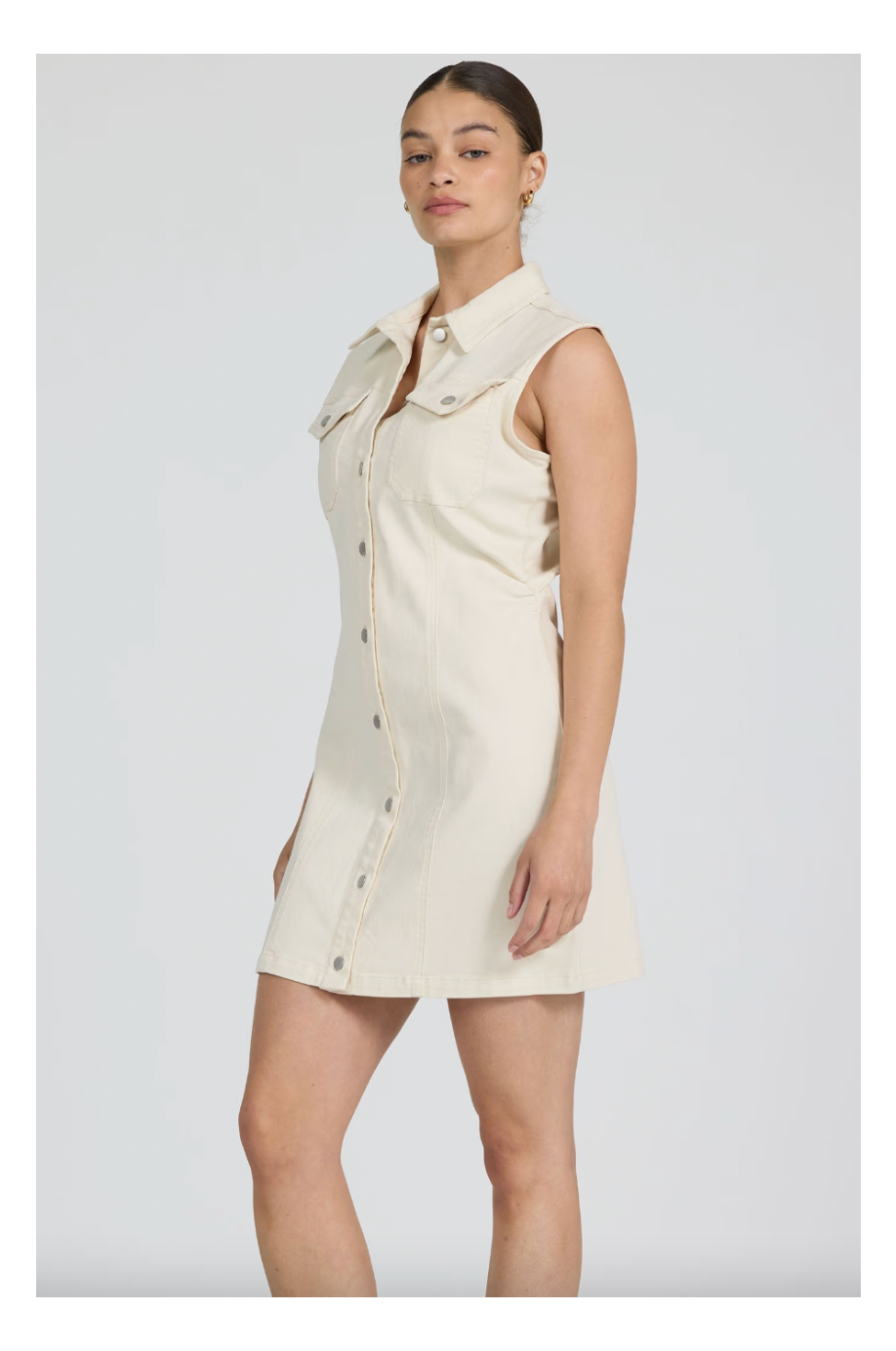 Woman wearing a beige sleeveless dress against a plain background