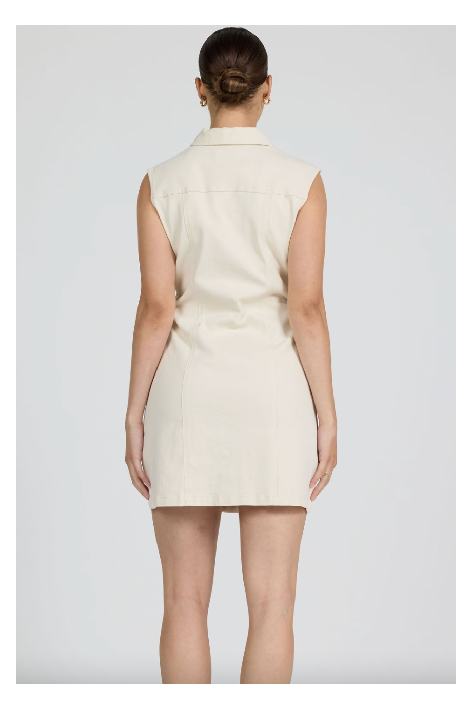 Person wearing a sleeveless beige dress against a white background